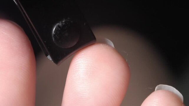 Close-up 4K footage of woman trimming toenails from beneath using a nail clipper