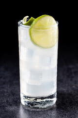 Gin Fizz cocktail with lime on black background