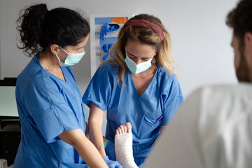 Doctors taking care of patient with broken ankle in hospital
