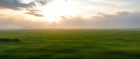 Misty sunrise illuminating vast green field: motion blur effect