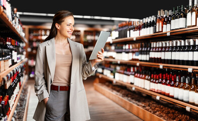 Confident businesswoman using digital tablet to manage liquor store and analyze retail KPI