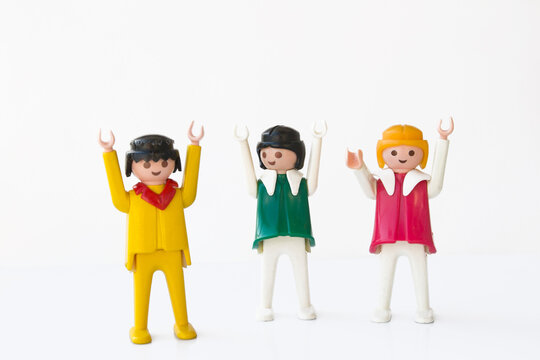 Figuras antiguas de Playmobil. Un chico y dos chicas con las manos arriba. Fondo blanco