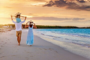 A holiday family walks down a beautiful beach in the tropics during sunset time as a travel and vacations concept