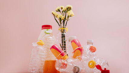 Conceptual balancing still life with plastic and flower on pink, theme of recycling, waste...