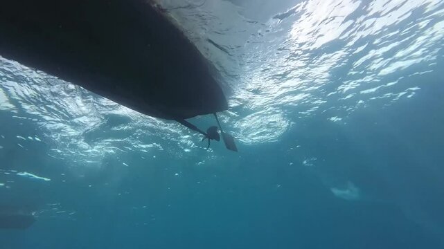 The engine is started on the boat and the propeller starts to rotate. A view from below of a moving boat with a propeller. A view from below of the bottom of a boat with a rotating propeller.