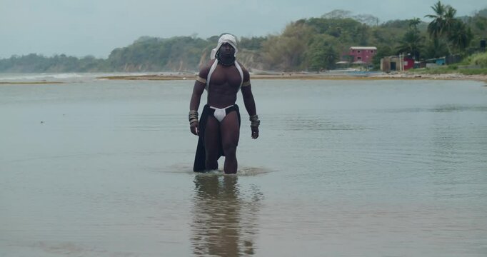 Muscles and dark skin define this male cosplayer on the beach.