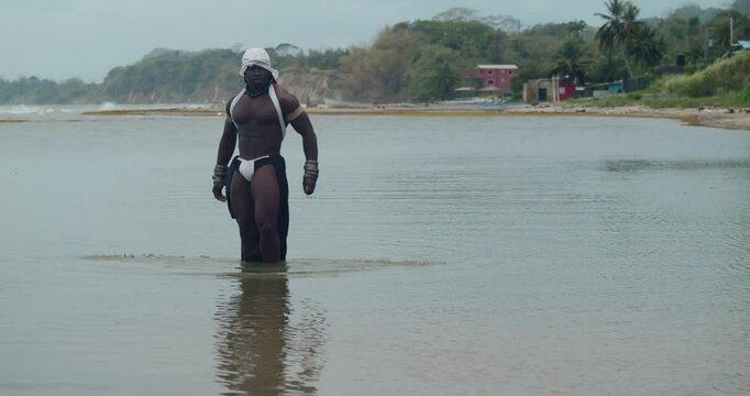 A male cosplayer, dark-skinned and muscular, by the sea.