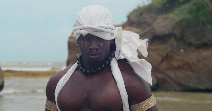 On the beach, a muscular, dark-skinned male cosplayer.