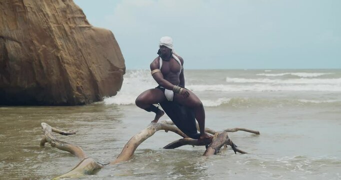 A muscular male cosplayer with dark skin at the beach.