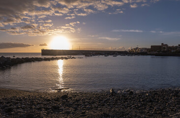 Golden sunset view of Playa de San Juan bay with protected sand beach and small harbor. Playa de San Juan is a small fishing village on the south west of Tenerife island.