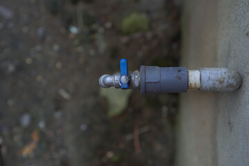 Close Up Of A Weathered Gray And Blue Metal Water Faucet Outdoors