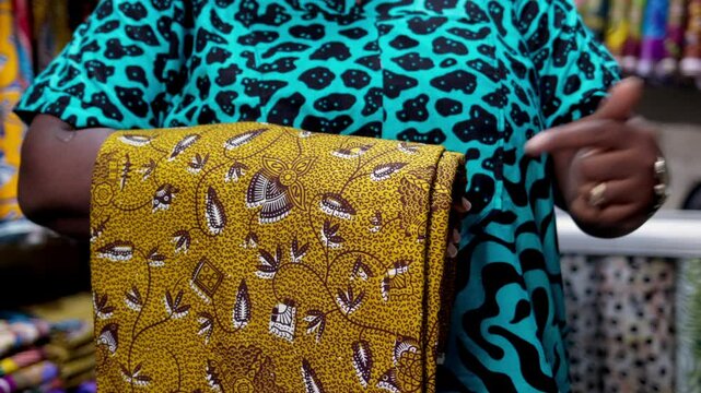 Business woman points at a piece of African Print, Ankara fabric in her textiles shop