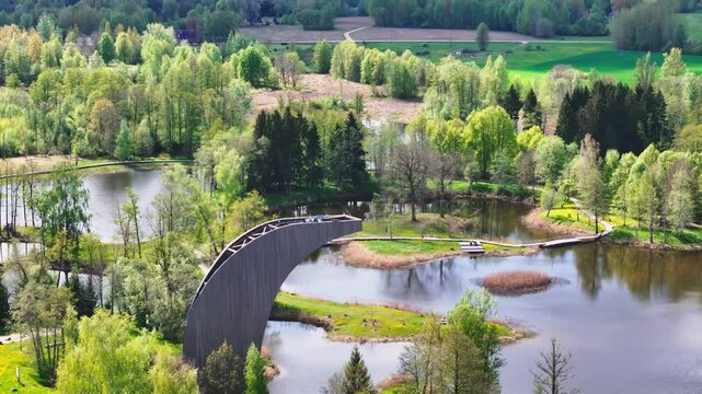 A Picturesque View From the Kirkilai Observation Tower Unveils Winding Boardwalks, Tranquil Karst Lakes, and Lush Forests in Biržai Regional Park, Lithuania - Aerial Pullback Shot