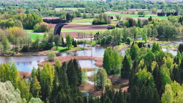 The Moon-shaped Kirkilai Observation Tower Provides Impressive Views of the Karst Lakes, Meandering Bridges, and Dense Foliage in Biržai Regional Park, Lithuania - Aerial Drone Shot