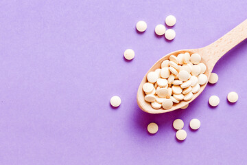 Heap of white pills on colored background. Tablets scattered on a table. Pile of red soft gelatin capsule. Vitamins and dietary supplements concept