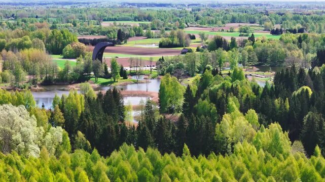 Biržai Regional Park, Lithuania - A Scenic View of the Karst Lake Framed by Dense Foliage, With the Kirkilai Observation Tower Rising in the Background - Aerial Drone Shot