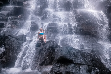 Beautiful adult girl in a natural waterfall incredible Bali landscape