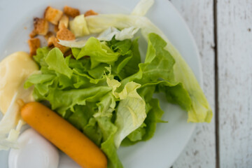 Green oak lettuce and sausage on a white dish. Top view