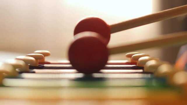 Close-up of mallets striking a colorful toy musical instrument. Capturing the joy of music and play in childhood.