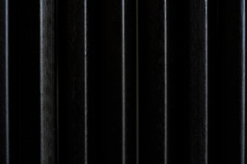 Close-up of black wooden pencils arranged in vertical lines, forming a modern striped pattern with soft light reflections. Minimalist artistic texture and creative vibe.