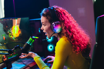 Funny female gamer involved in an online video game session with professional streaming equipment