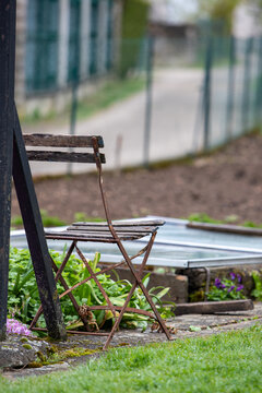 Une vieille chaise est au premier plan, avec un potager en pr&eacute;paration &agrave; l'arri&egrave;re-plan. Couche chaude enterr&eacute;e dans un potager au printemps. 