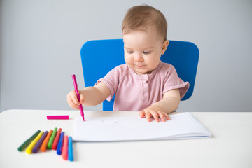 little girl draws with colored markers. Toddler development