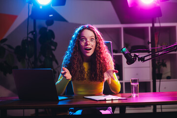 Popular blogger live streaming with neon lighting in modern setup, expressing excitement during online broadcast