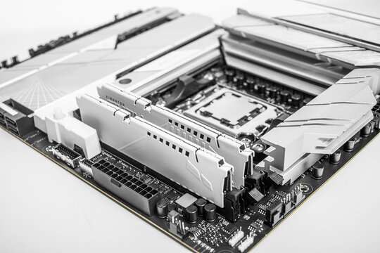 High-performance motherboard showing two installed RAM modules with a sleek heatsink design in a black-and-white color scheme.