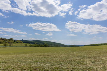 Open landscape. A large field is turning green and there is a stack of straw on the field. The sky...