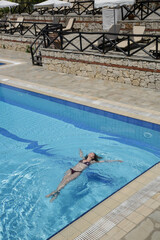 Young woman floating in the large resort swimming pool	