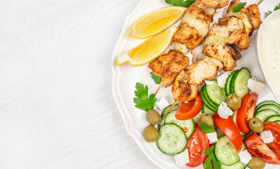 chicken kebab or souvlaki. Mediterranenan healthy lunch greek salad, tzatziki yogurt sauce chicken skewers on white background, top view, copy space