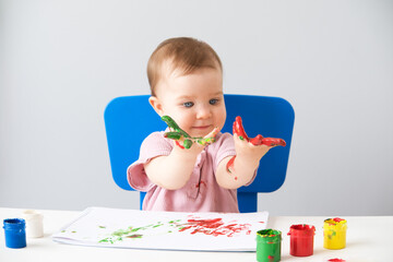 child is drawing on white sheets with finger paints