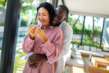 Happy and diverse couple sharing a joyful moment at home, embracing and smiling together