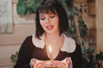 birthday cake with one candle, a girl makes a wish on her birthday