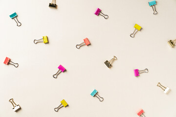 Colorful binder clips scattered on a beige background