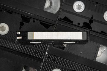 A collection of VHS tapes with one prominently displayed blank-labeled cassette.