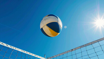 A volleyball soars over the net under a bright blue sky and shining sun