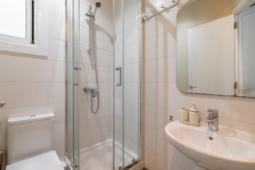 Compact bathroom interior with white tile walls glass shower enclosure and minimal decor