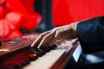 Men's hands play the keys of an electronic piano.