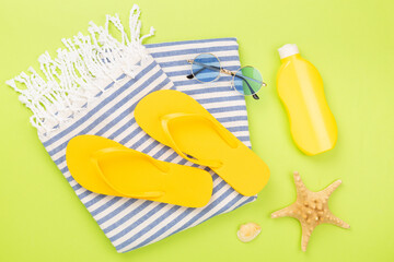 Beach towel with summer accessories on color background, top view