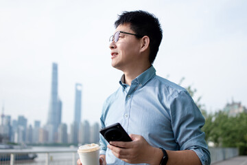asian businessman using smart phone while having coffee