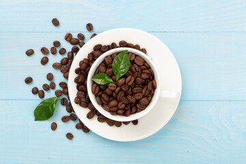 Roasted coffee beans with leaves on wooden background,top view