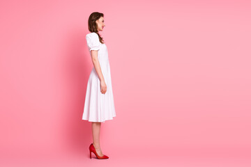 Stylish young woman in a white dress on a pink background highlighting elegance and fashion for lifestyle and glamour