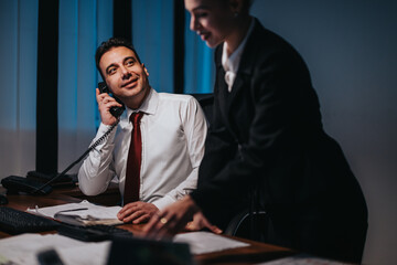 Two business people are working together in an office, discussing work-related matters and...