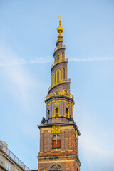 The corkscrew spire of the Church of Our Saviour in Copenhagen rises prominently against a clear blue sky. Its intricate design showcases a blend of architecture and artistry.