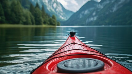 A close-up of a red kayak paddle against a scenic mountain lake backdrop