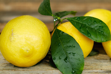Lemons with fresh leaves on wooden cutting board. 