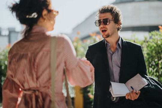 Two business people engage in a spirited discussion outside the office. The setting is outdoors, and the interaction is animated and engaging. - Powered by Adobe