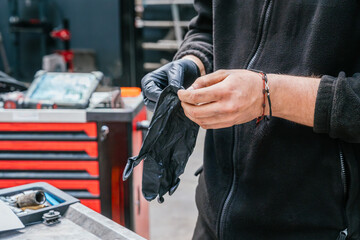 Mechanic putting on black protective gloves before automotive maintenance work